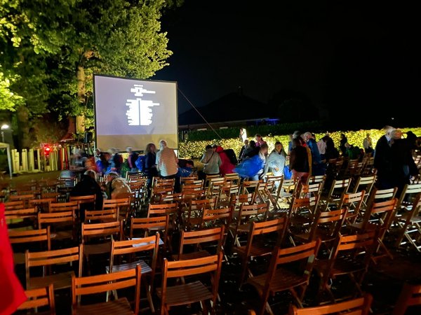 Menschen verlassen den Reitplatz im Dunkeln bei Filmende